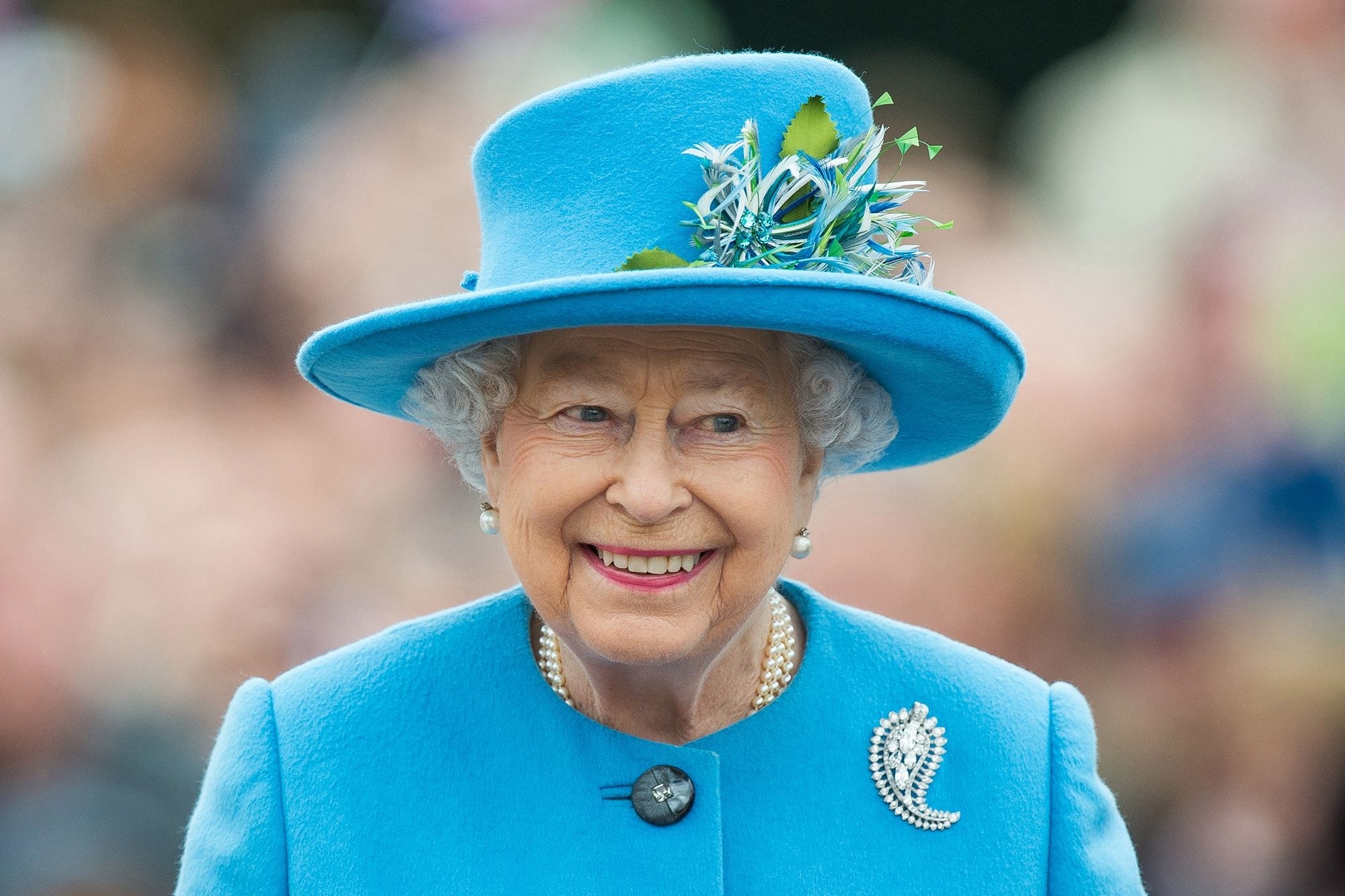 queen looking very happy and wearing an ugly broach