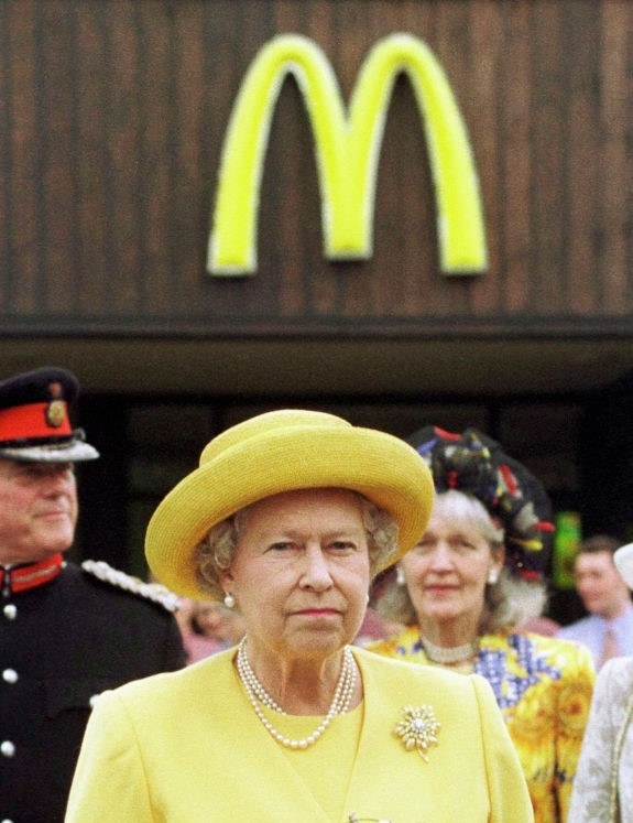 the queen standing proudly in front of a mcdonalds she apparently owns i guess