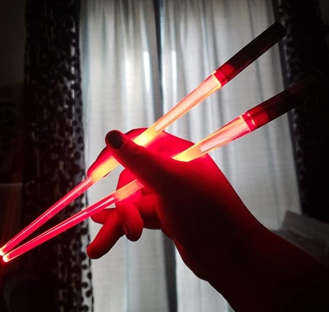 the reviewer&#x27;s image of the set of lightsaber chopsticks