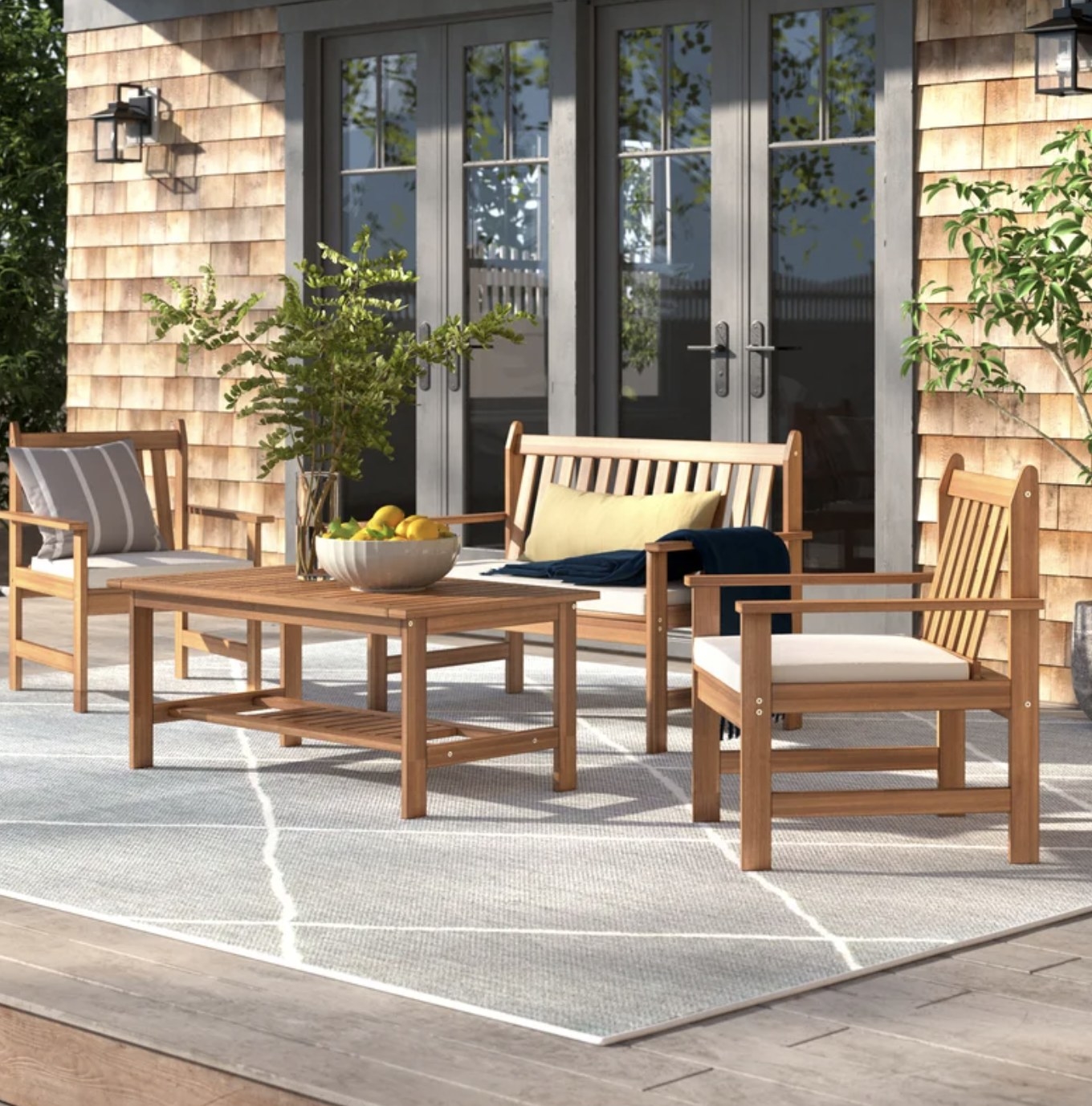 The light brown table, bench and chair set with white cushions are outside with the sun shining directly on them