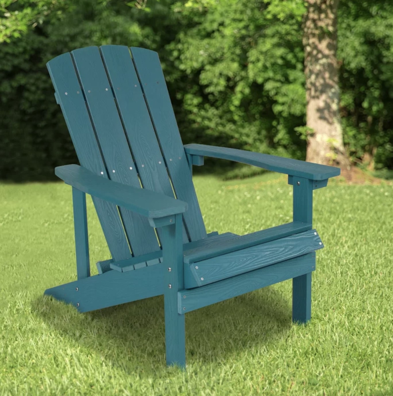 The blue wood-like chair is outside in a grassy area