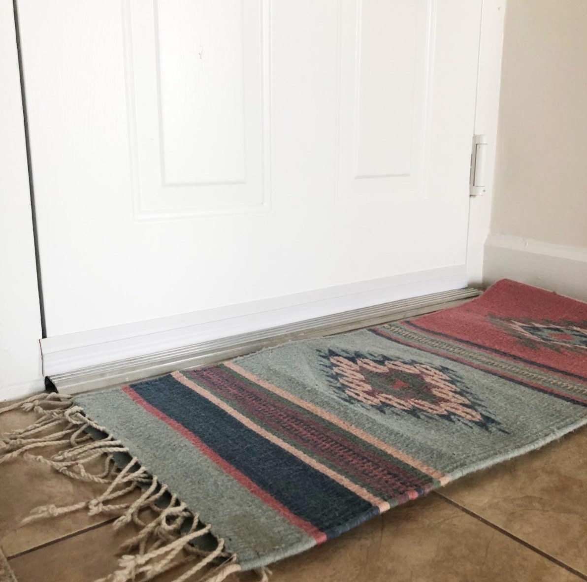 the reviewer&#x27;s image of the draft door stopper with a rug in front