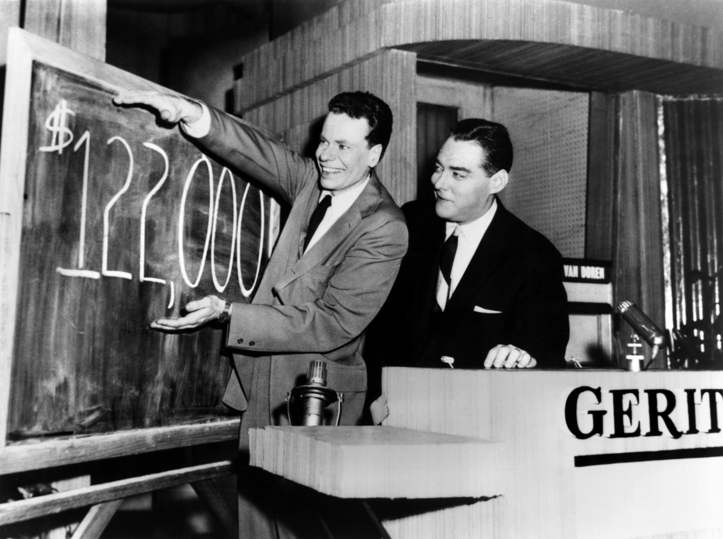 Van Doren standing next to a blackboard displaying his winnings, which were at that point $122,000