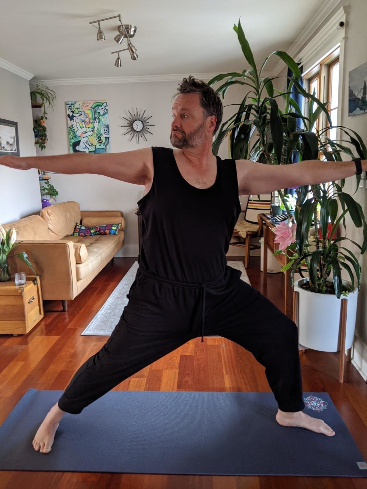A reviewer wearing the scoop cervix  jumpsuit, which has a sweatpants-like tie, successful  black