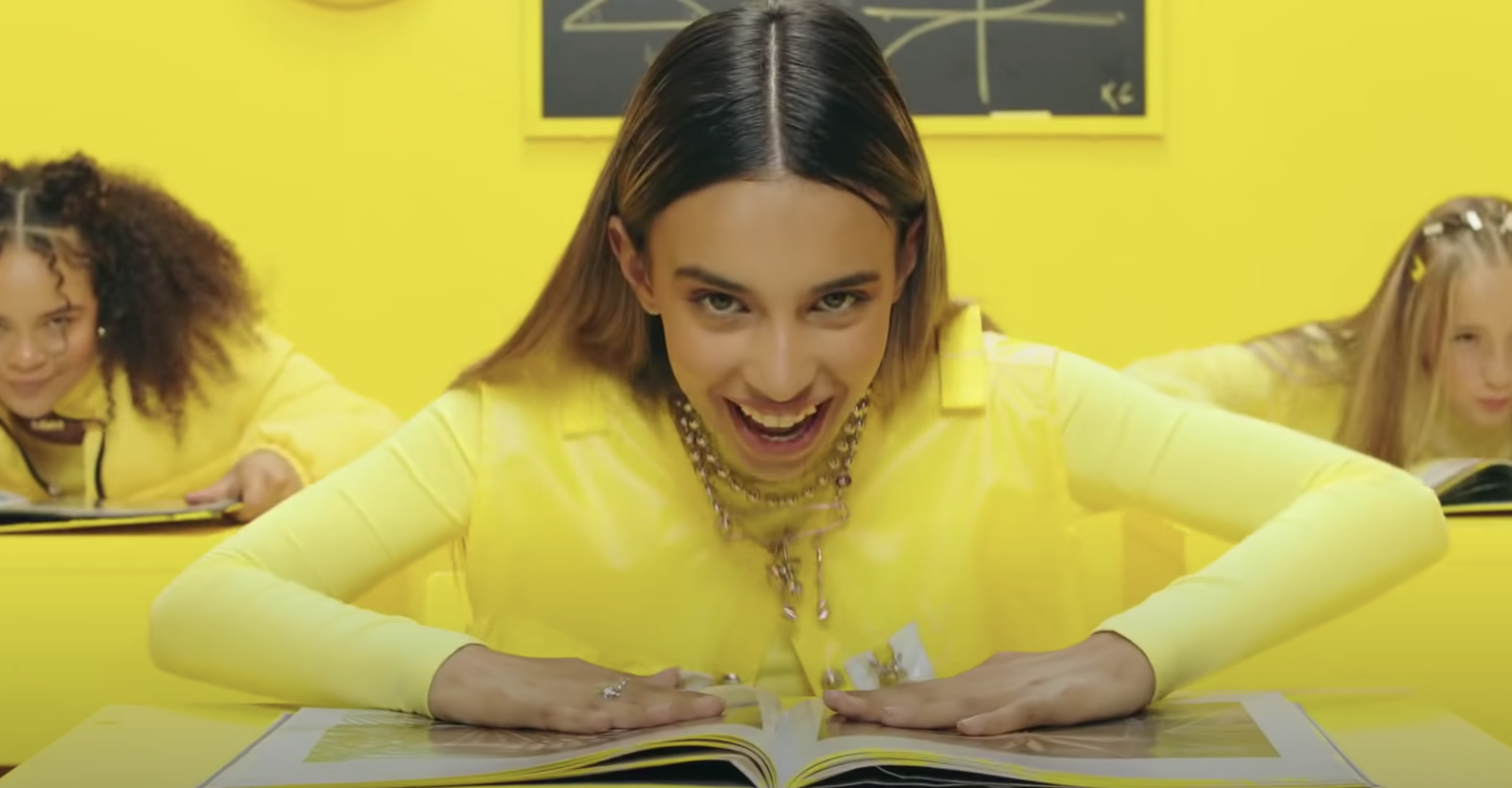 Kylie Cantrall is smiling wide at a desk with two others behind her