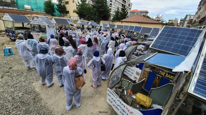 A crowd of women surrounded by their food carts, listens to Wajdi speak