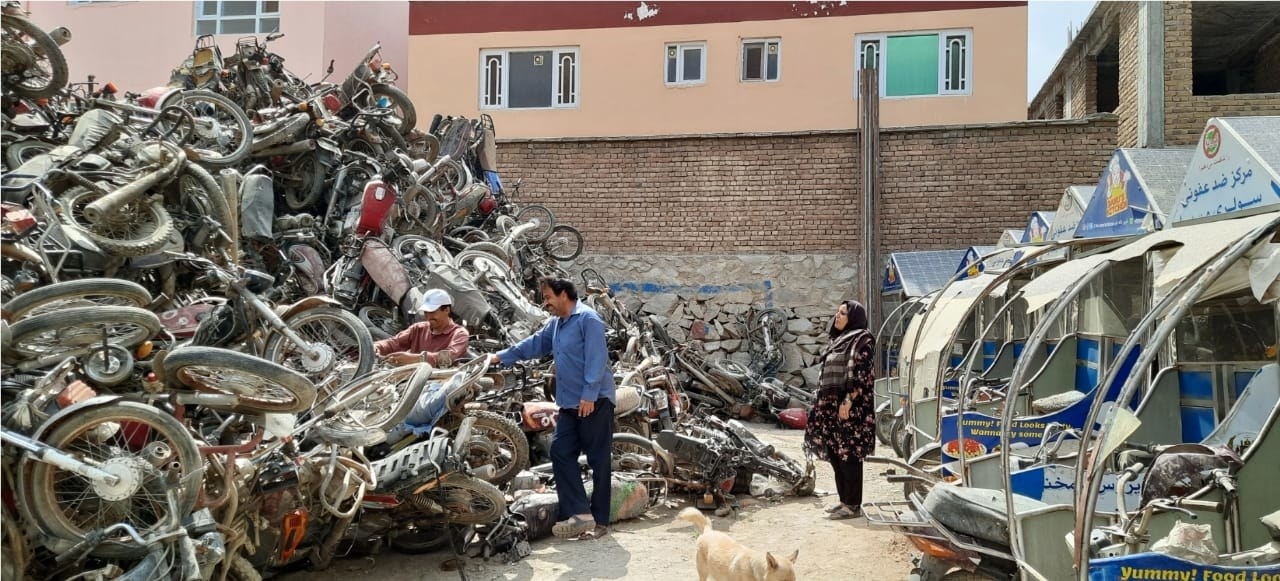 Wajdi&#x27;s parents stand between a large mountain of bicycles and the parked food carts from their nonprofit