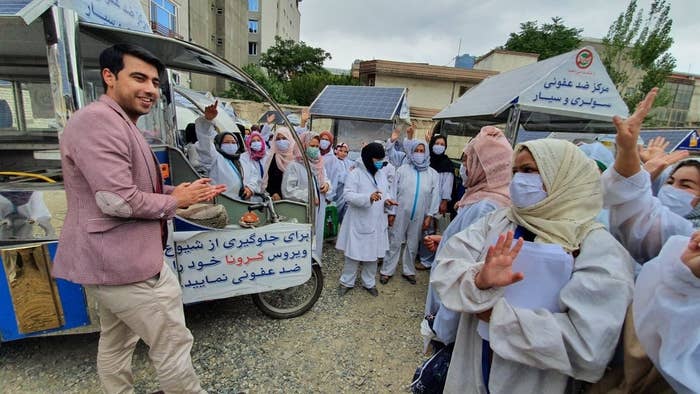 Wajdi, in Afghanistan, greets women surrounded by the food carts they run