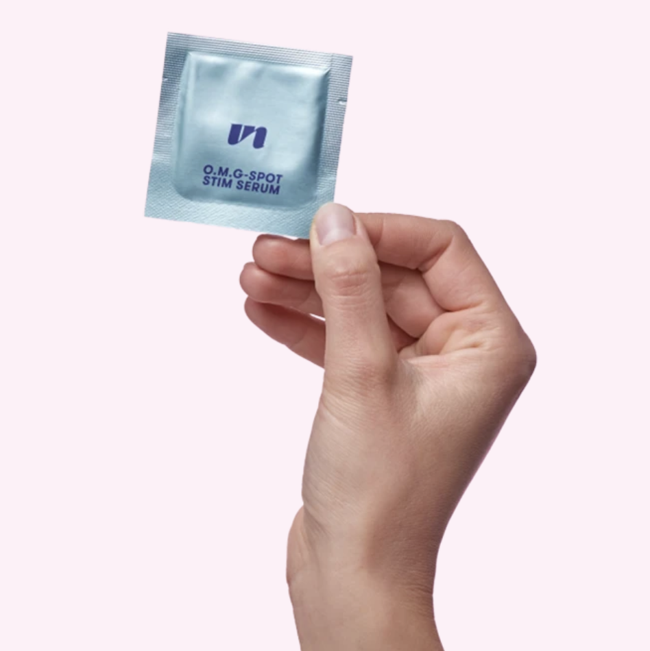 Model holding foil packet of O.M.G-Spot Stim Serum