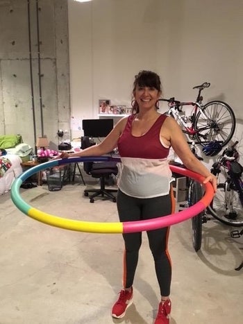 reviewer with rainbow weighted hula hoop on waist