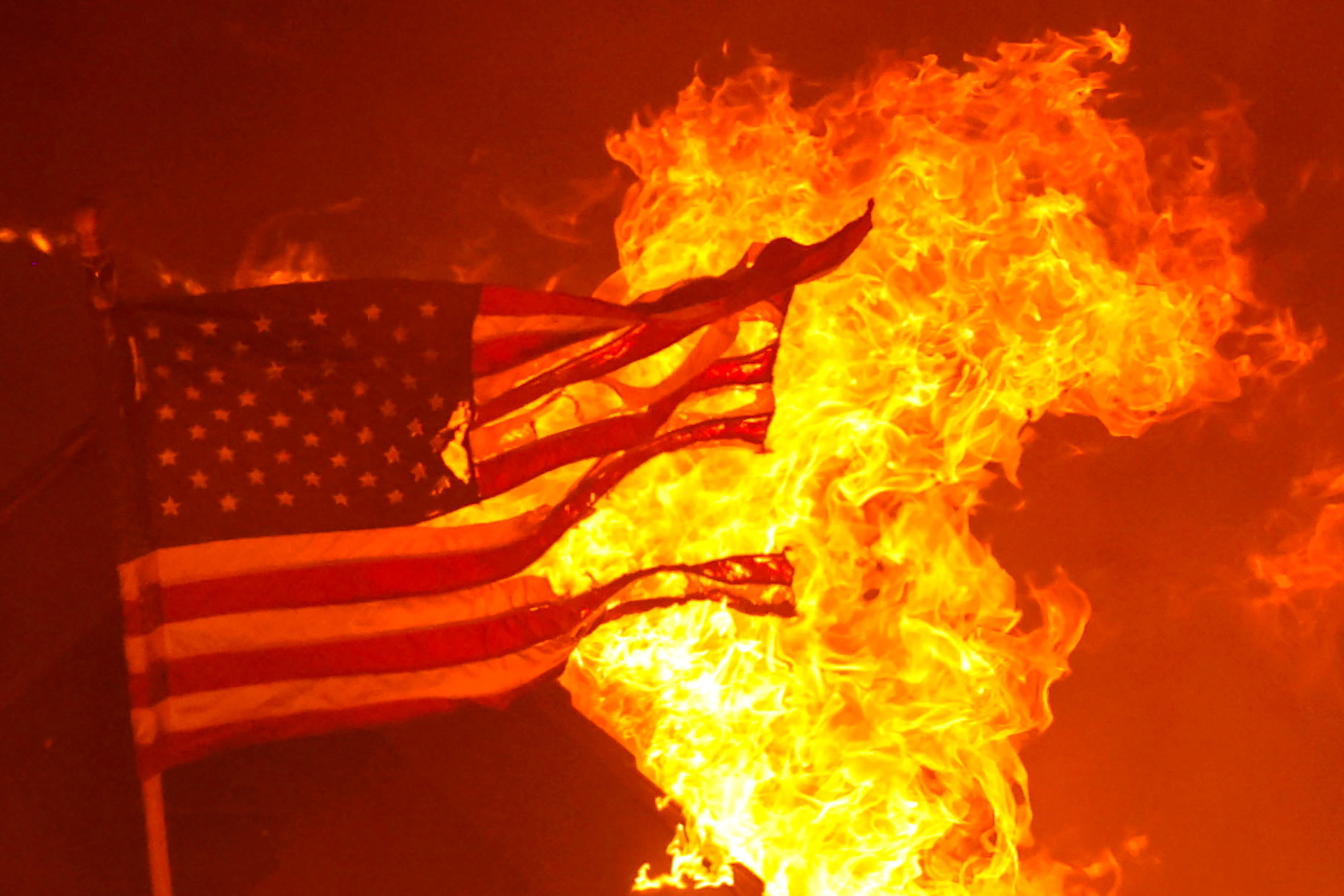 A tattered US flag burns at night