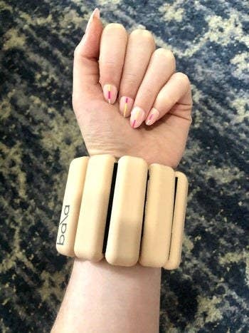 BuzzFeed writer's arm with the beige bangle wrapped around their wrist