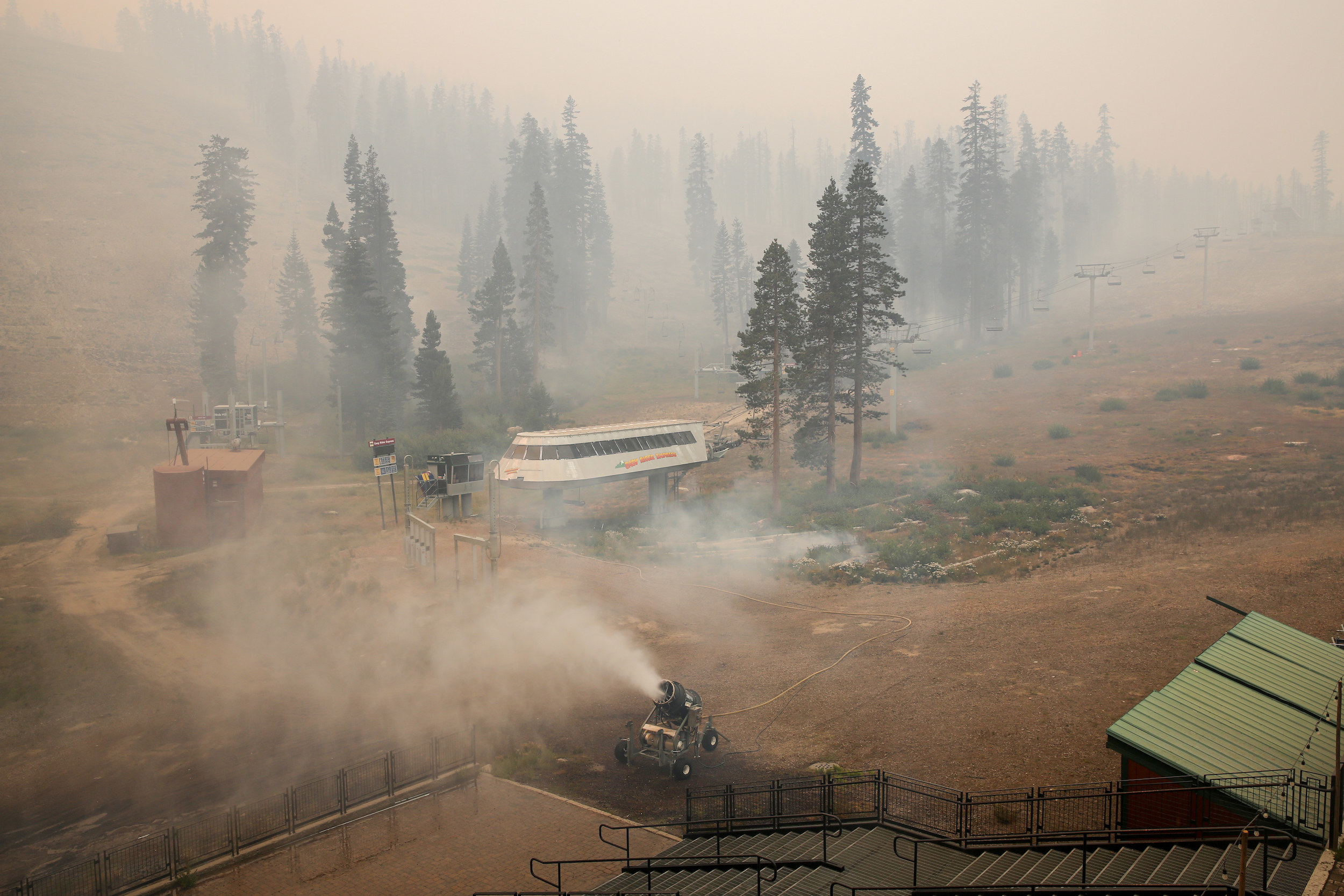 A cylindrical machine on wheels blows clouds over a dirt-covered hill