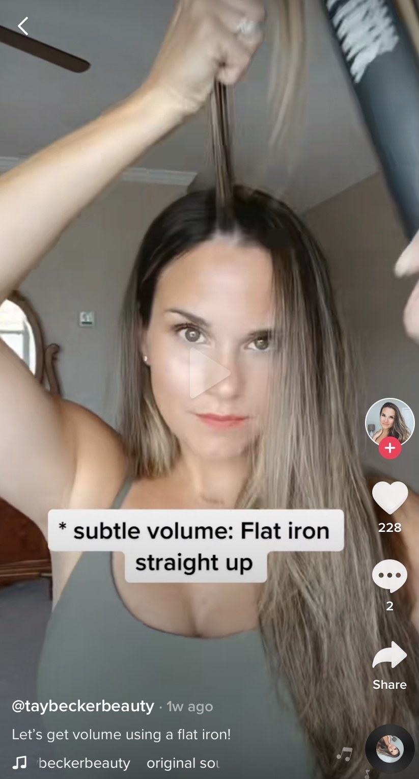 A woman on TikTok using a flat iron to create volume in her hair