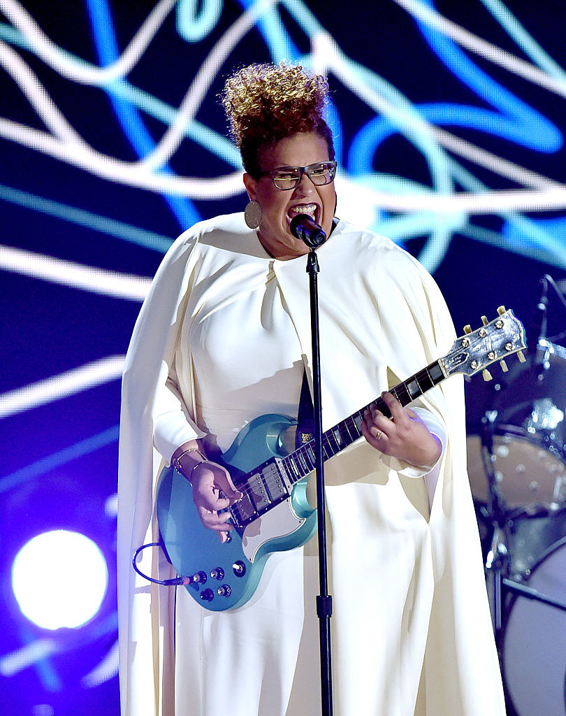 Howard playing guitar and singing in a white dress at the Grammys