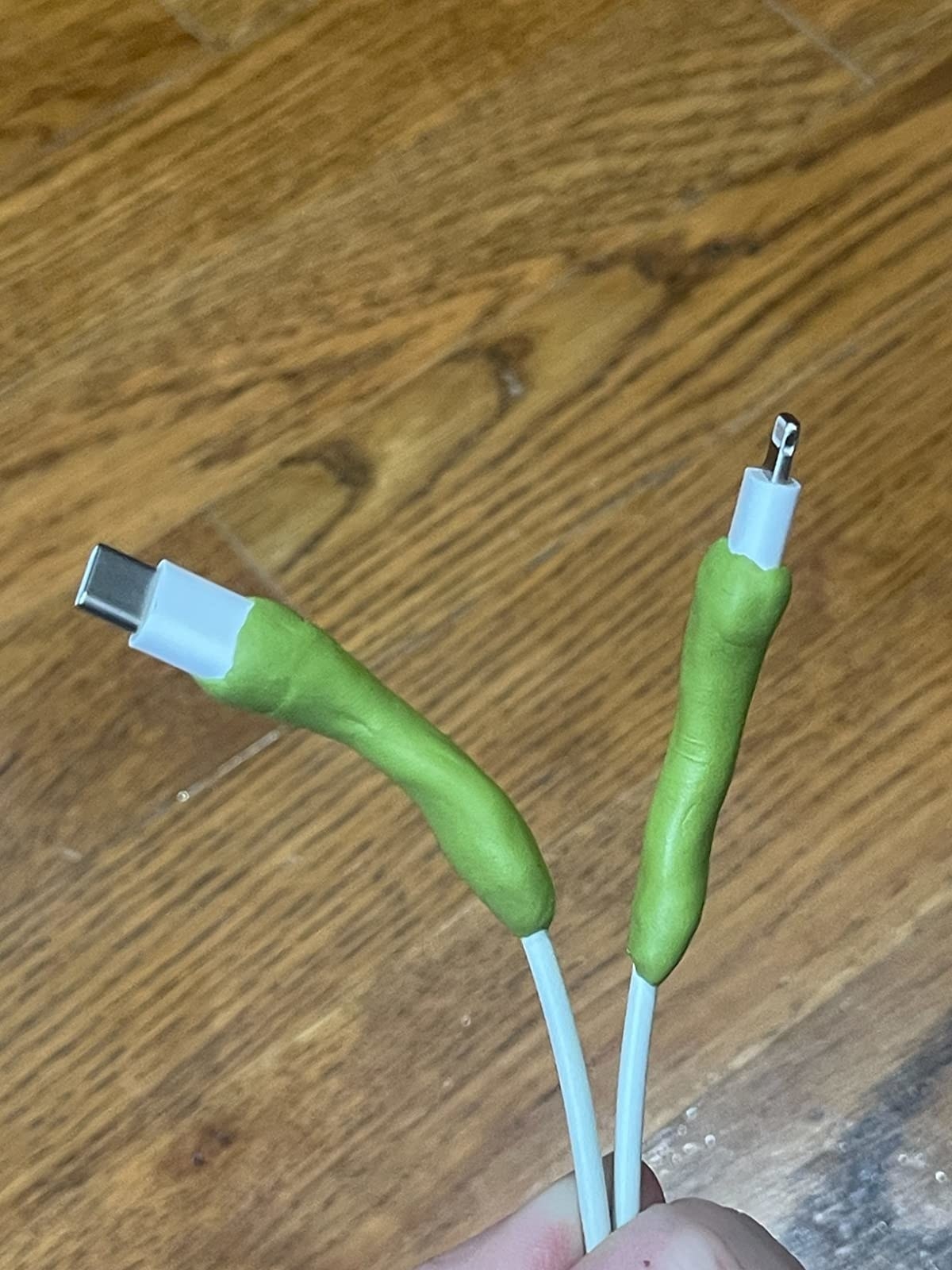reviewer holding up two cords with green moldable glue on the ends