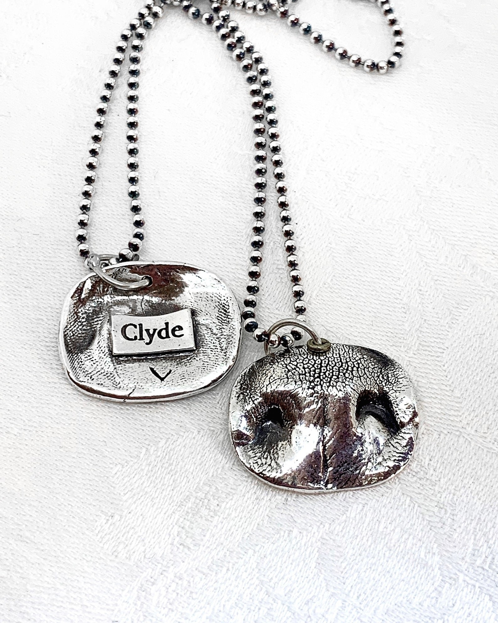 silver necklace on a chain with a 3D dog nose and the dog&#x27;s name on the other side