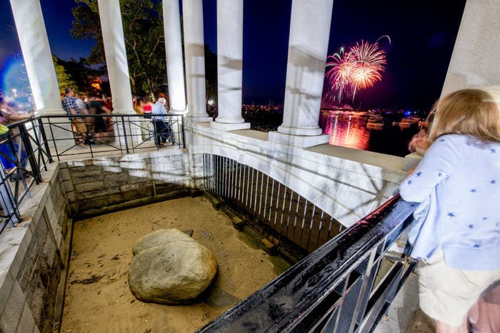 A woman looking at Plymouth Rock