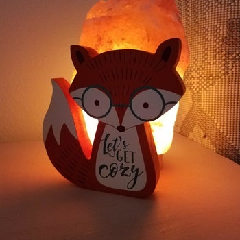 Reviewer's photo showing the Himalayan salt lamp behind a wooden fox