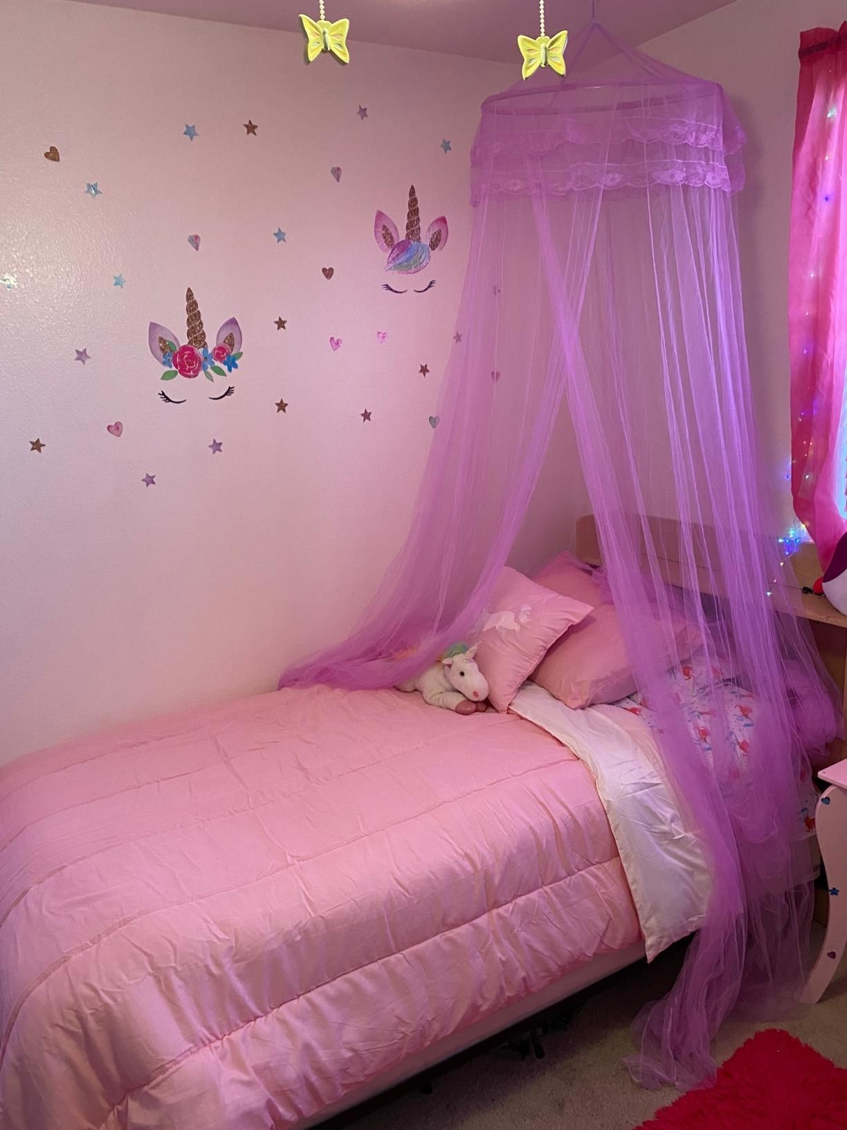 Reviewer's photo showing the sheer canopy in purple installed over their child's bed