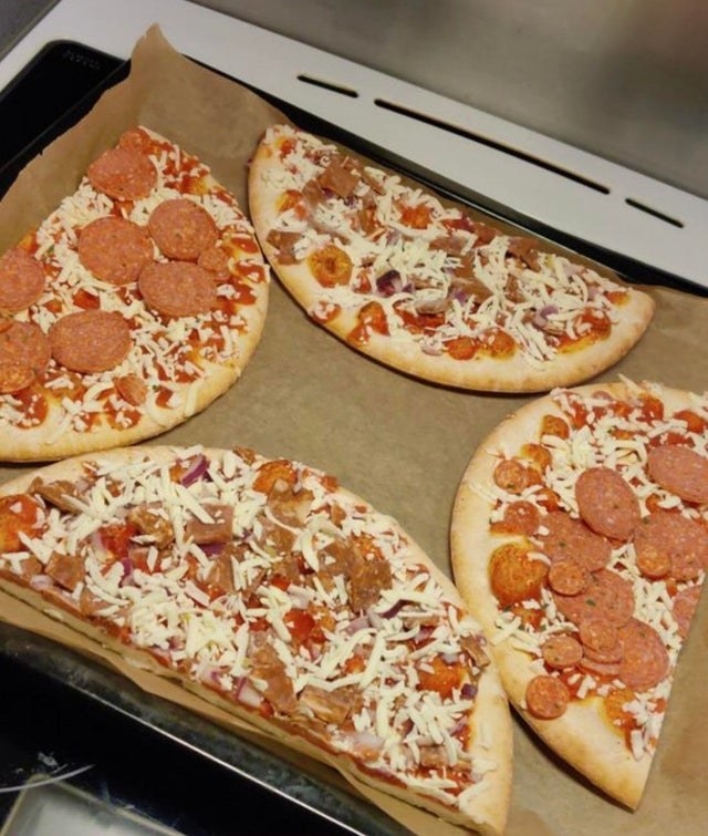 Four halves of frozen pizza on a sheet pan
