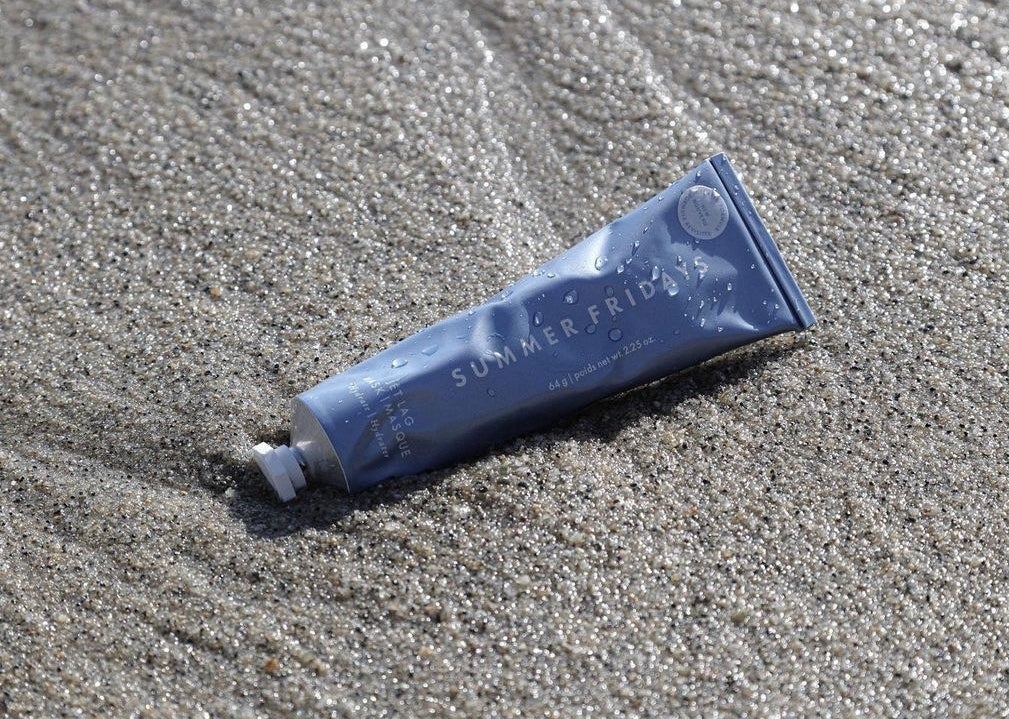 A tube of the face mask nestled nicely on some wet sand
