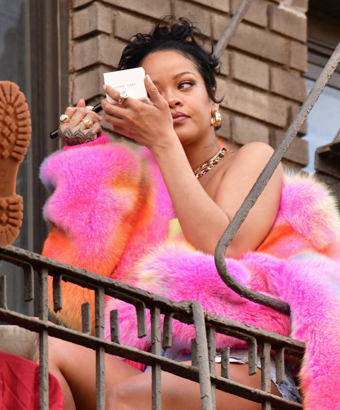 Rihanna is pictured applying makeup on the set of her music video