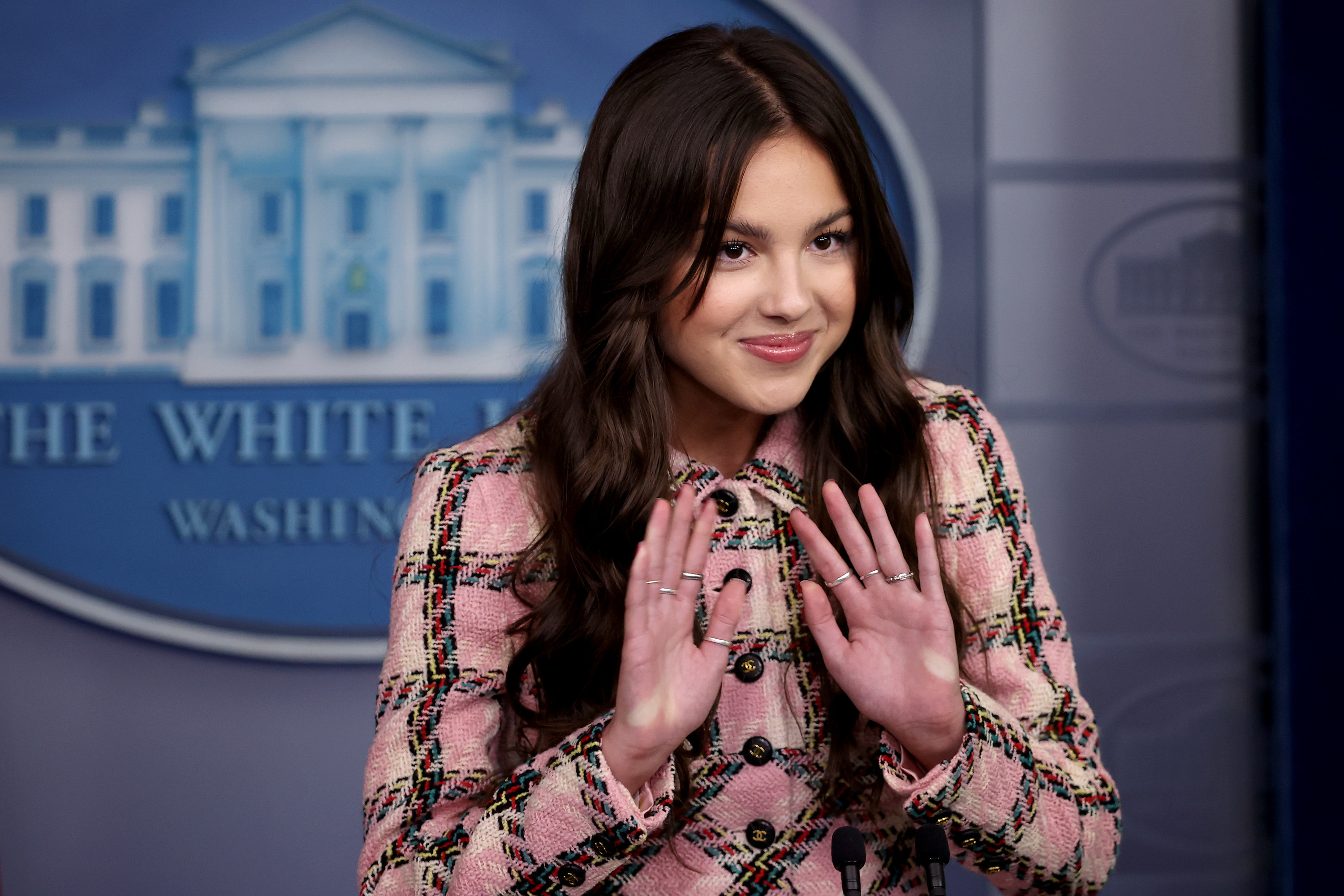 Olivia speaking in the White House press room in a plaid outfit