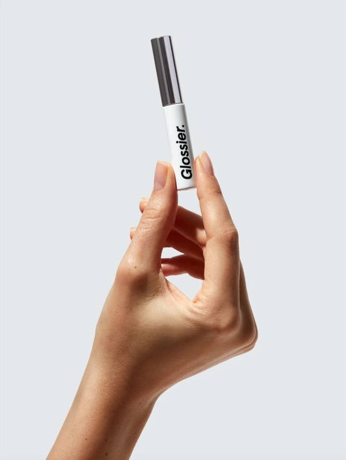 the Glossier boy brow eyebrow fluffer being held in a model&#x27;s hand