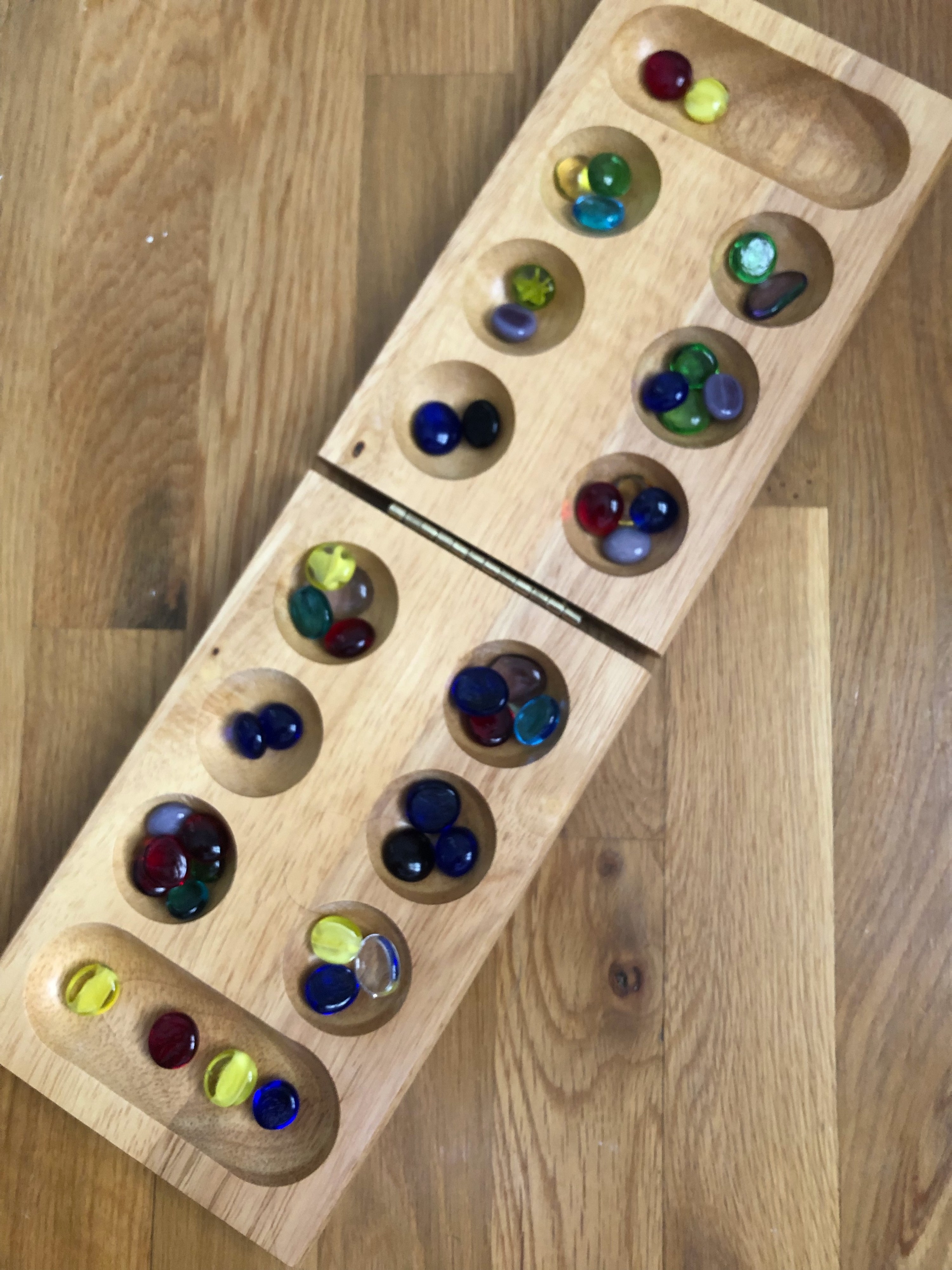 Mancala board filled with colorful marbles in every pocket