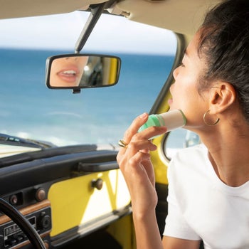 model applying the stick to her face in a car