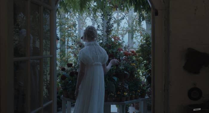 The back of Emma in a long gown facing a gorgeous archway of flowers