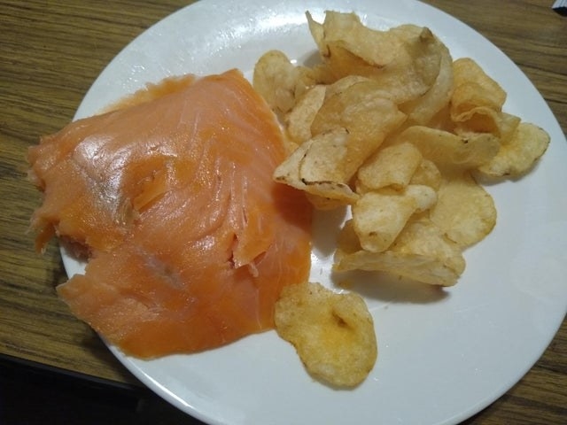 A piece of smoked salmon with potato chips