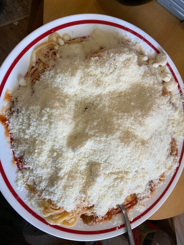 A plate of spaghetti with a ton of Parmesan cheese