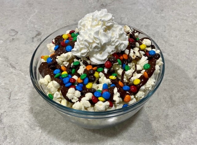 A bowl of popcorn with ice cream toppings