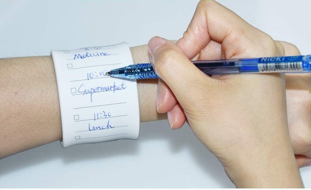 model writing on wrist dry erase board with a blue pen