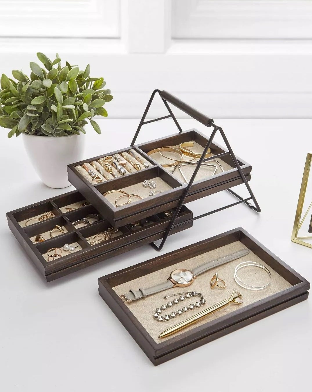 A brown jewelry box holding a watches, bracelets, earrings, and rings.