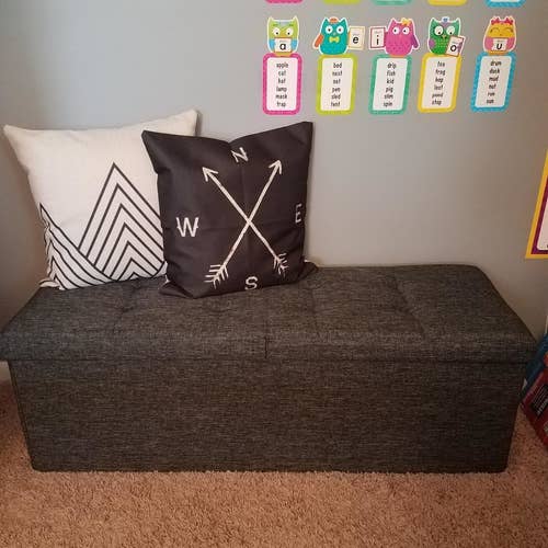 Reviewer's photo showing the dark grey ottoman decorated with cushions in their kid's playroom