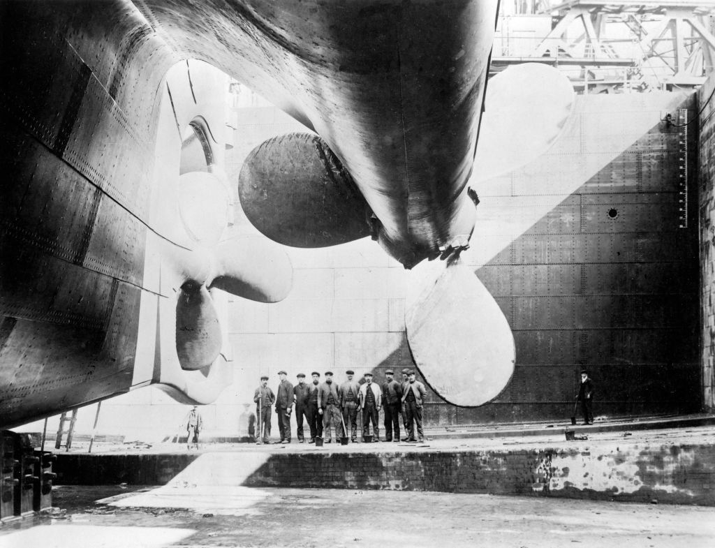A large propeller with several working men standing beneath it