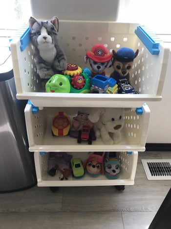 Reviewer's photo showing the white organizer with three bins holding toys and stuffed animals