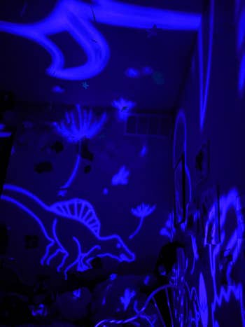 Reviewer's photo showing the dinosaur images projected on the wall by the lamp