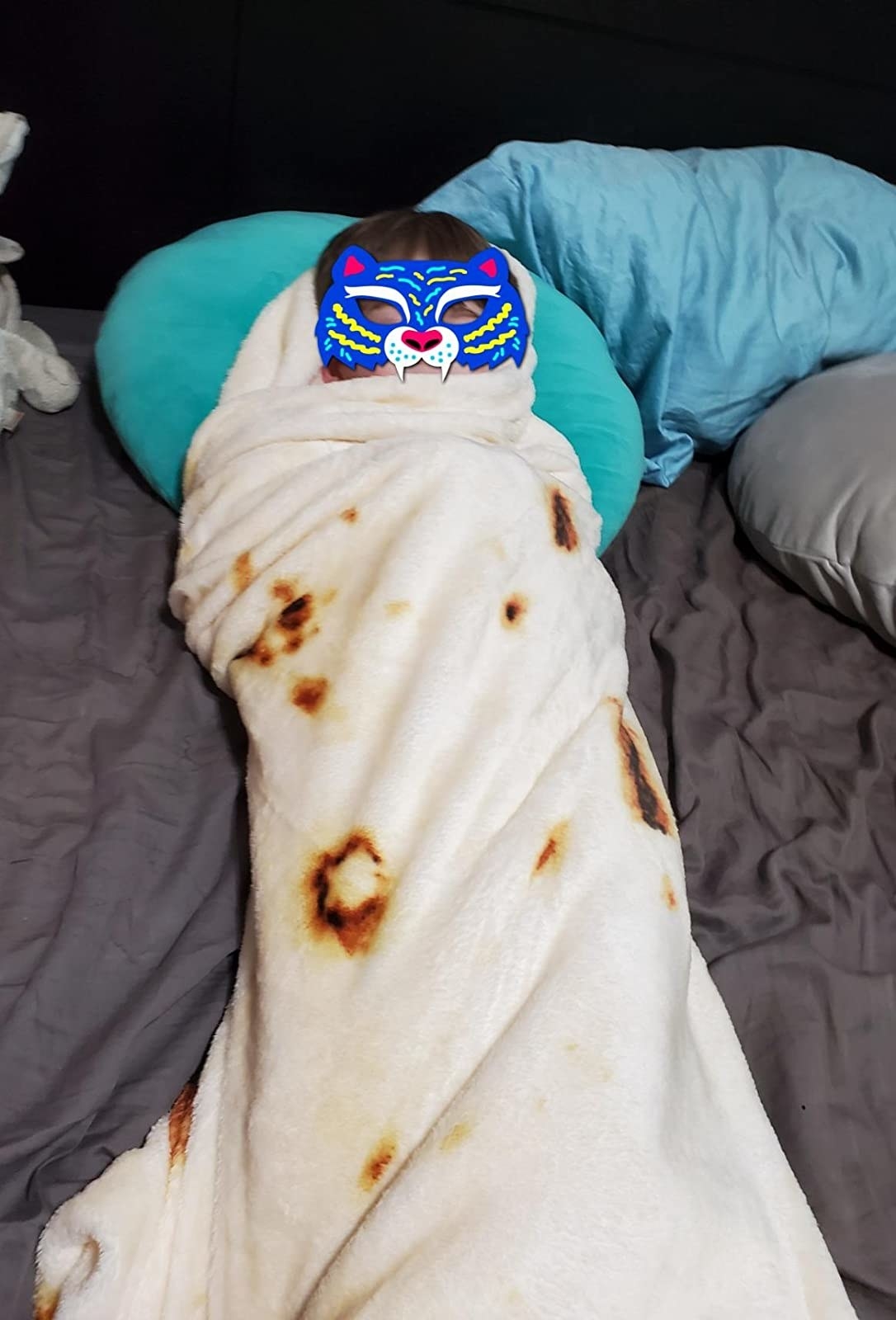 Reviewer's photo showing their child wrapped like a burrito in the tortilla blanket