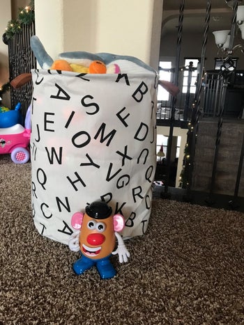 Reviewer's photo showing the canvas bin in letter print holding toys