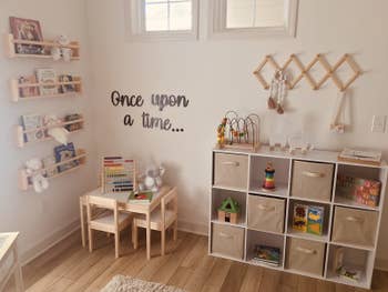 Reviewer's photo showing the beige fabric storage cubes in their shelving unit in the playroom