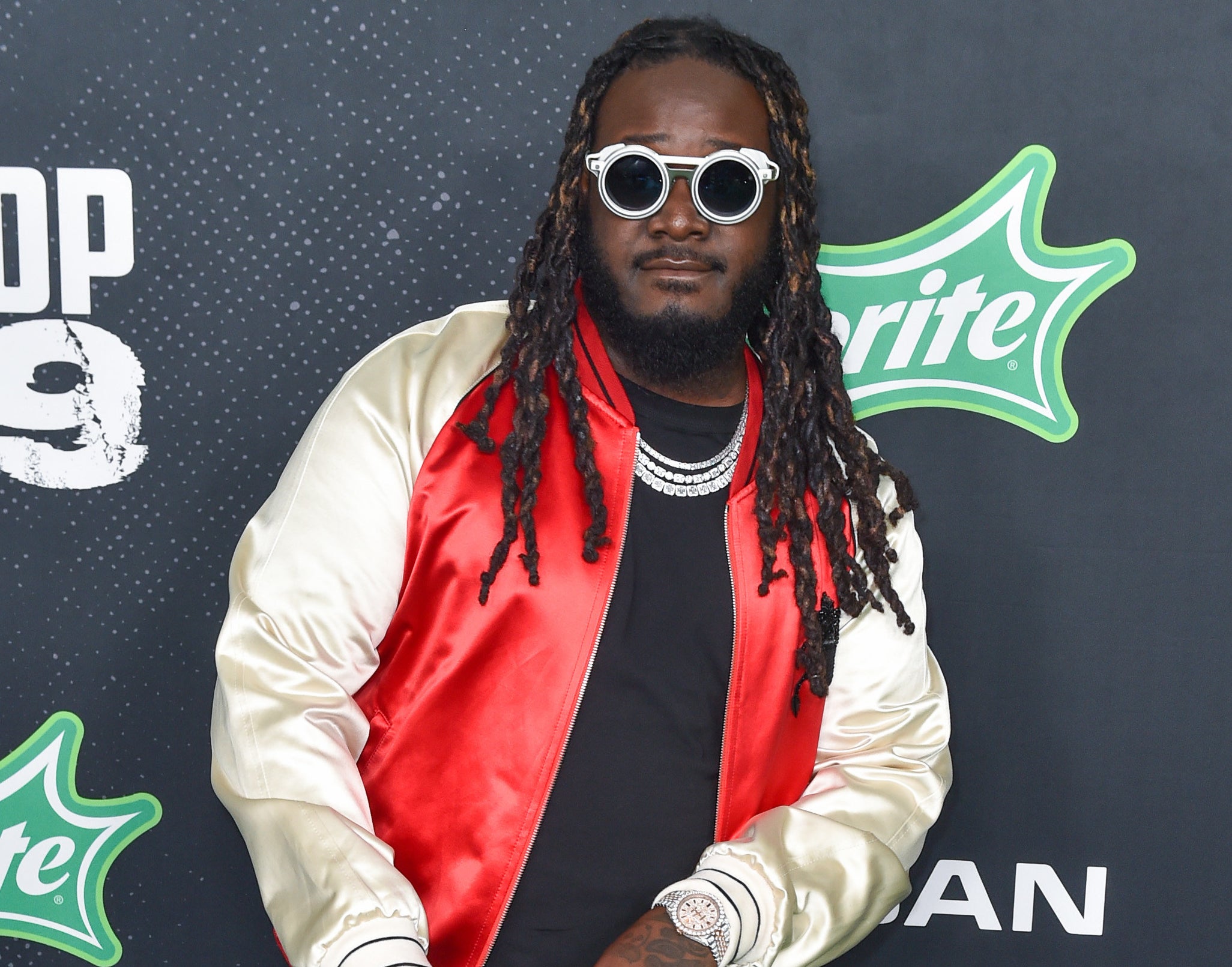 T-pain wears sunglasses and a red and gold varsity jacket to a red carpet
