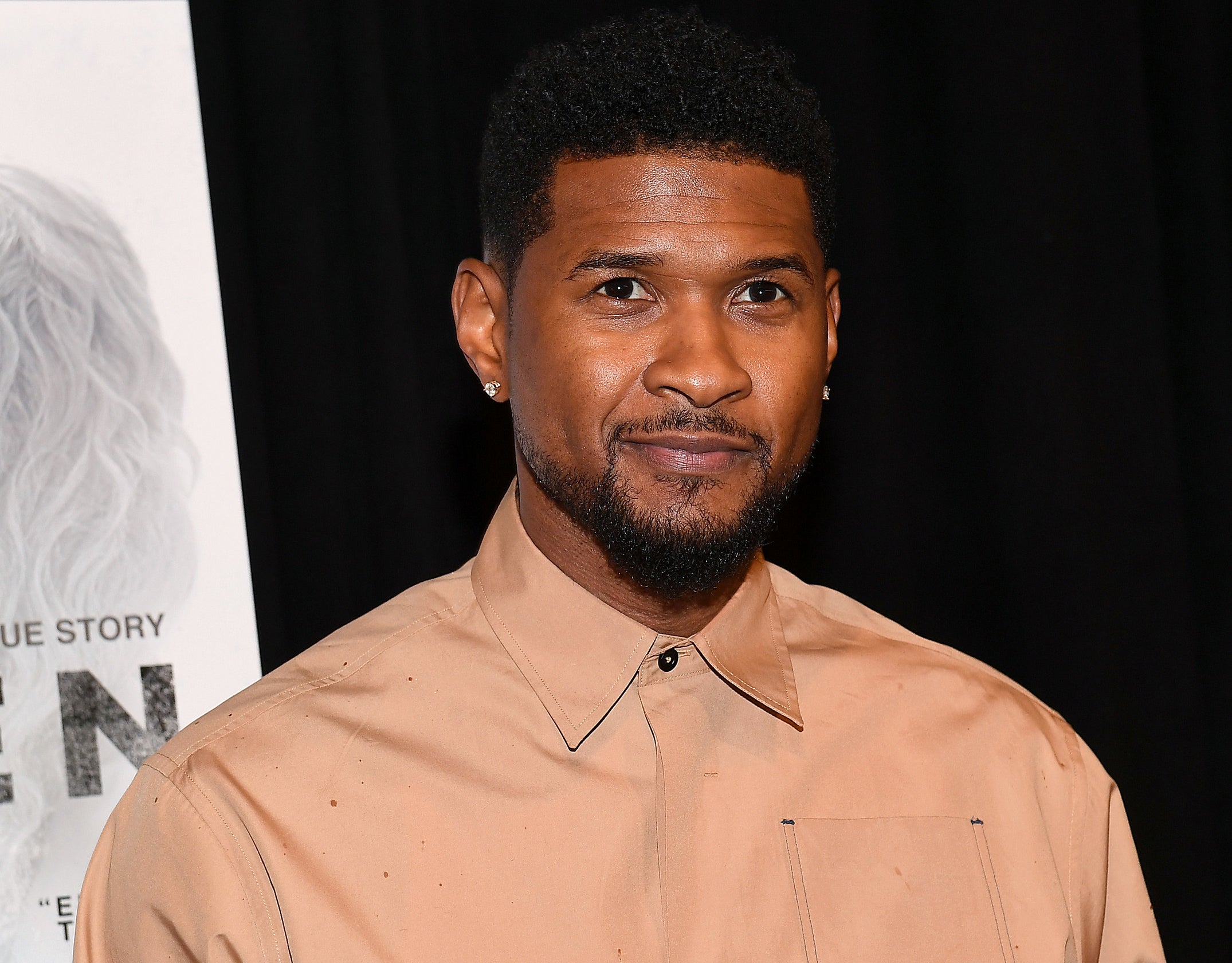 Usher looks serious while wearing a beige button down