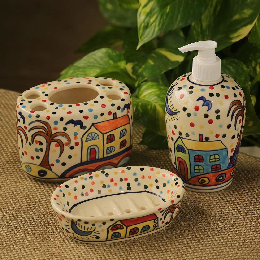 A soap dish, liquid soap dispenser, and a toothbrush holder, with houses and polka dots painted on them