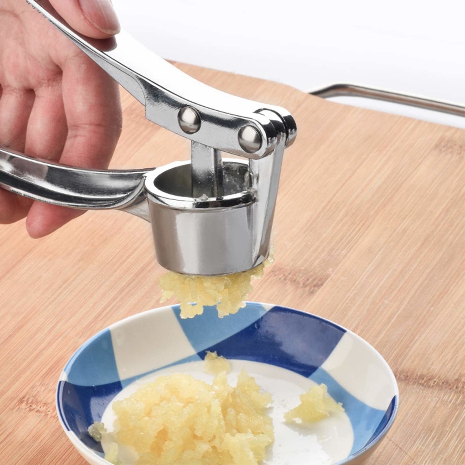 A person using the crusher to mince garlic