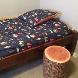 Reviewer using the tree trunk stool as a side table near their bed
