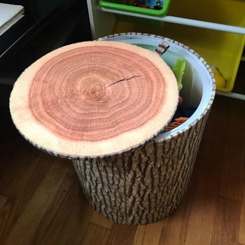 Reviewer using the tree trunk stool as a storage bin with the lid open